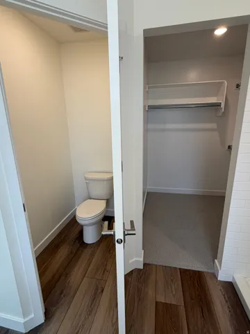 Bathroom featuring a walk in closet, dark wood finished floors, and recessed lighting