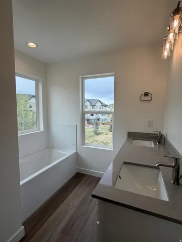 Bathroom featuring double vanity, dark wood-type flooring, a garden tub, and recessed lighting