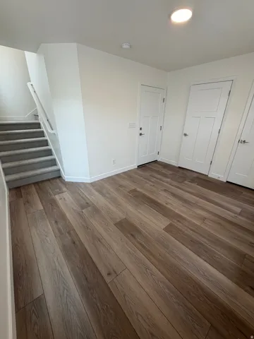 Unfurnished bedroom with dark wood-style flooring and baseboards