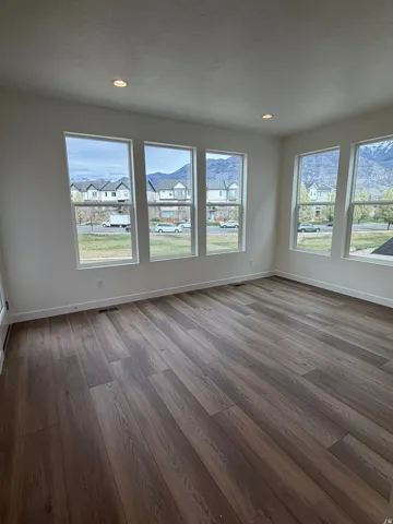 Empty room featuring dark wood-style flooring, healthy amount of natural light, and recessed lighting