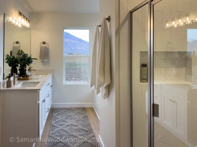 Full bathroom featuring double vanity, a stall shower, and light wood-style floors