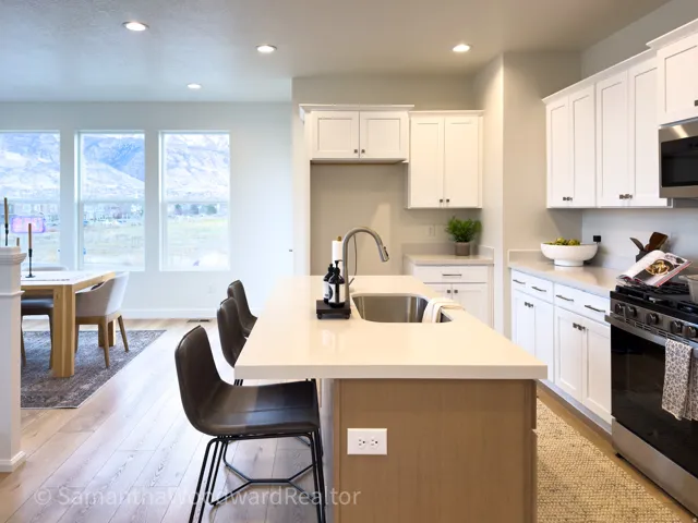 Kitchen with gas range, a breakfast bar, a center island with sink, white cabinets, and recessed lighting