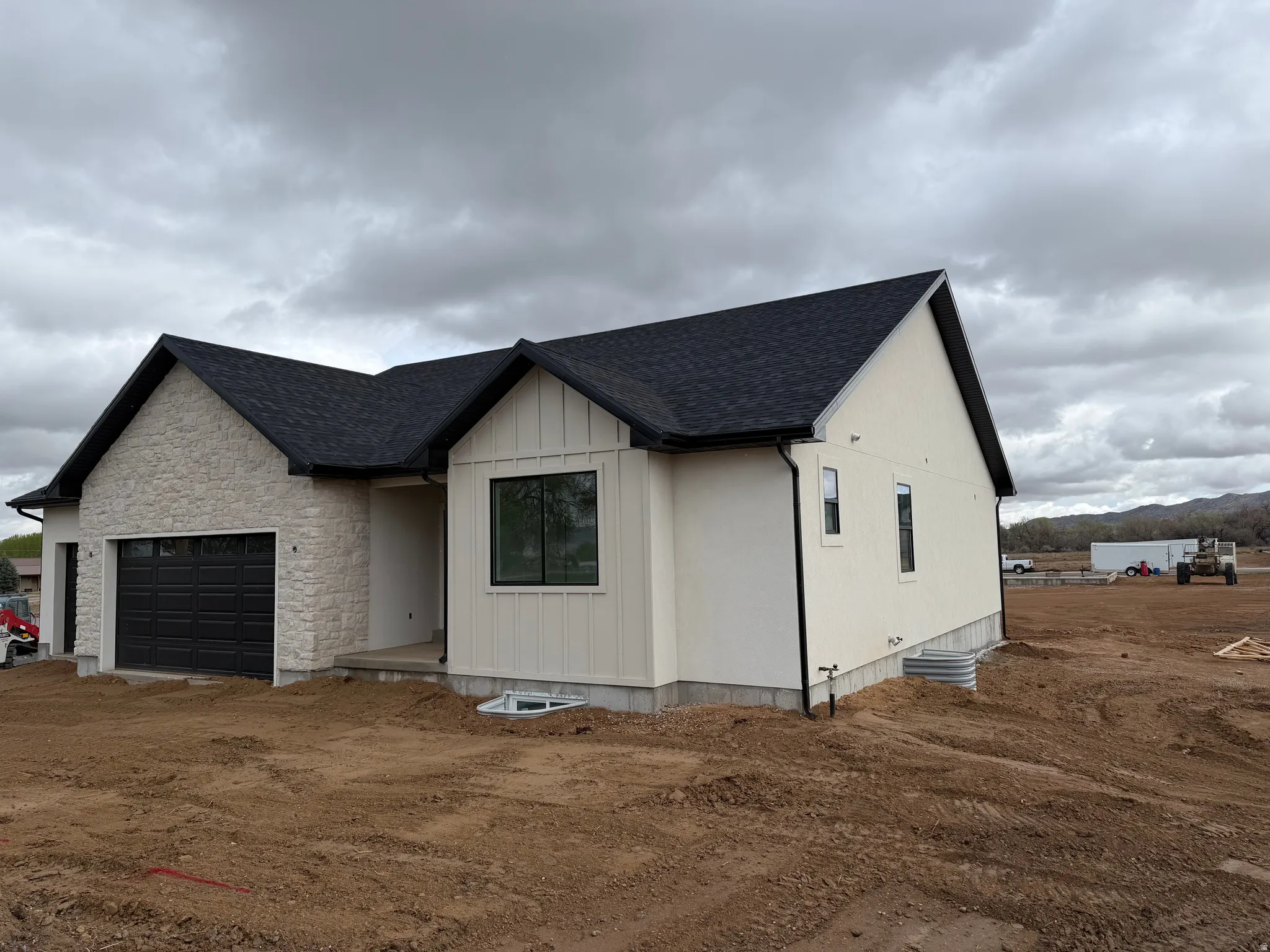 Modern inspired farmhouse featuring roof with shingles, an attached garage, stone siding, and dirt driveway
