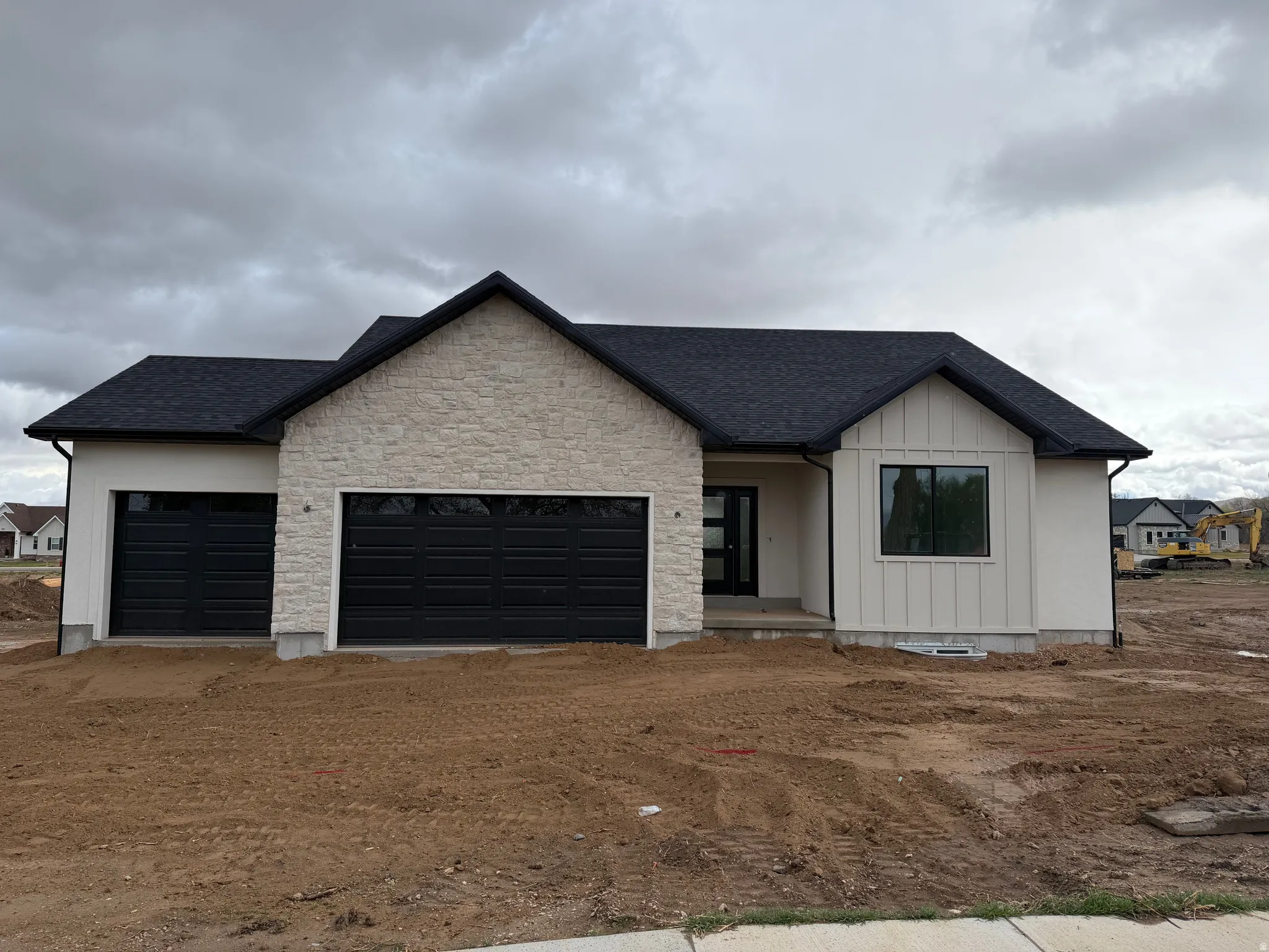 View of front of property featuring roof with shingles, an attached garage, dirt driveway, and board and batten siding