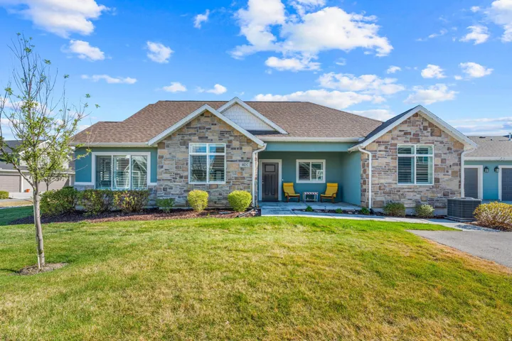View of front facade featuring stone siding, a front lawn, a porch, and a shingled roof