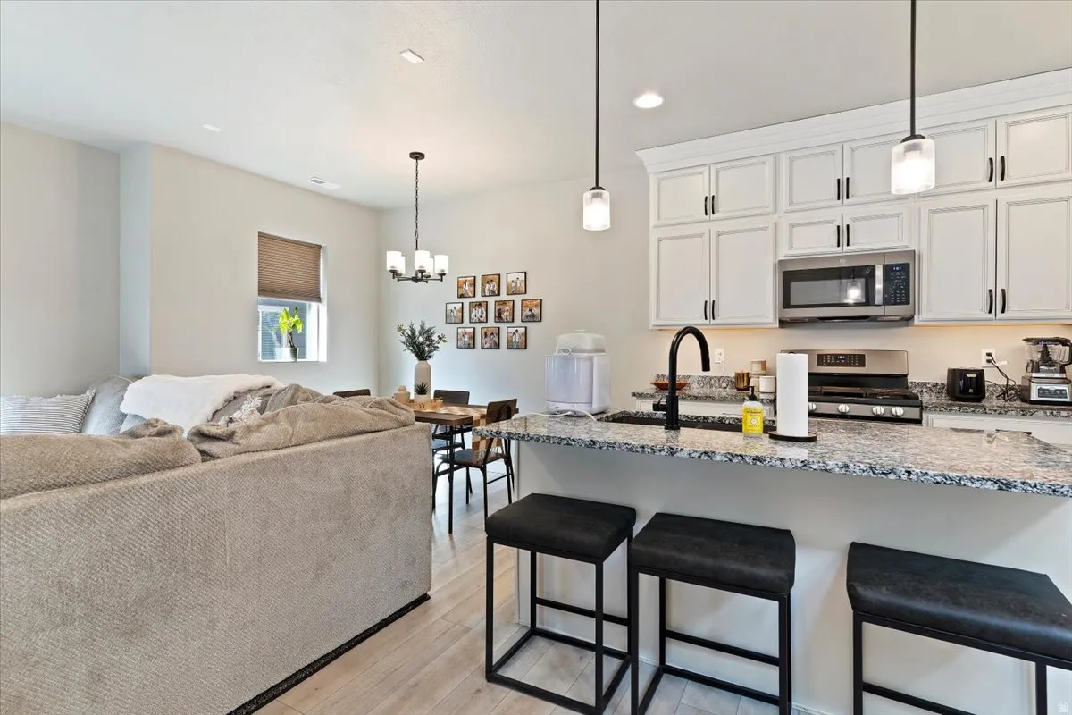 Kitchen with a breakfast bar, light stone counters, white cabinetry, and stainless steel appliances