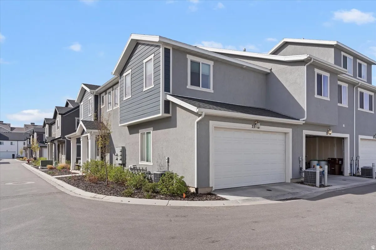 View of property exterior with stucco siding, a residential view, and a garage