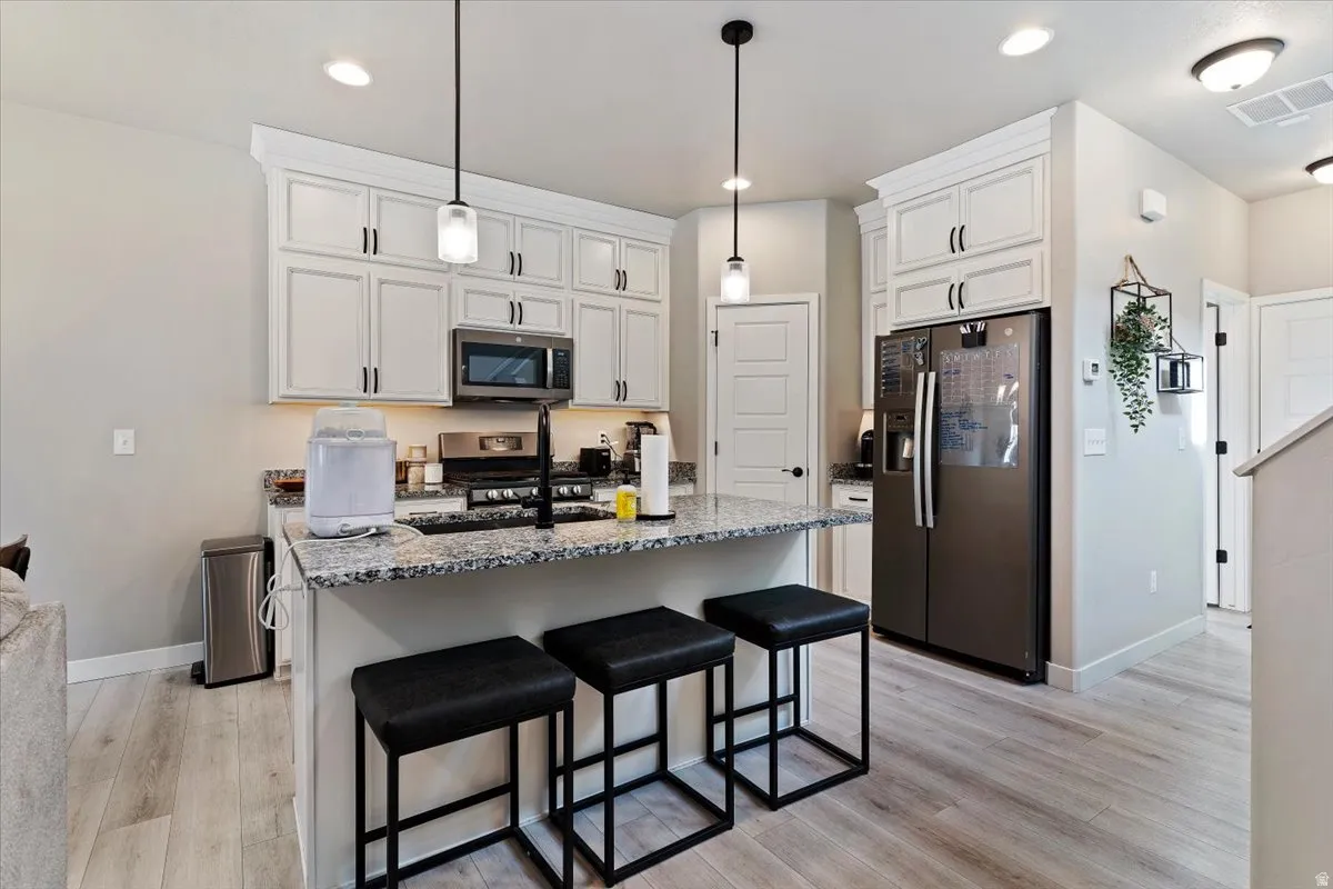 Kitchen with stainless steel appliances, a kitchen bar, dark stone counters, and a center island with sink