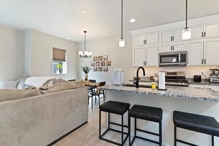 Kitchen with a breakfast bar, light stone counters, white cabinetry, and stainless steel appliances
