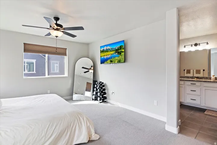 Bedroom featuring dark carpet, ensuite bathroom, a ceiling fan, and dark tile patterned floors