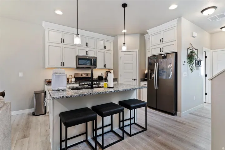 Kitchen with stainless steel appliances, a kitchen bar, dark stone counters, and a center island with sink