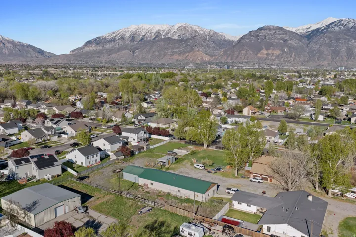 Aerial view of property and surrounding area featuring a mountainous background and nearby suburban area