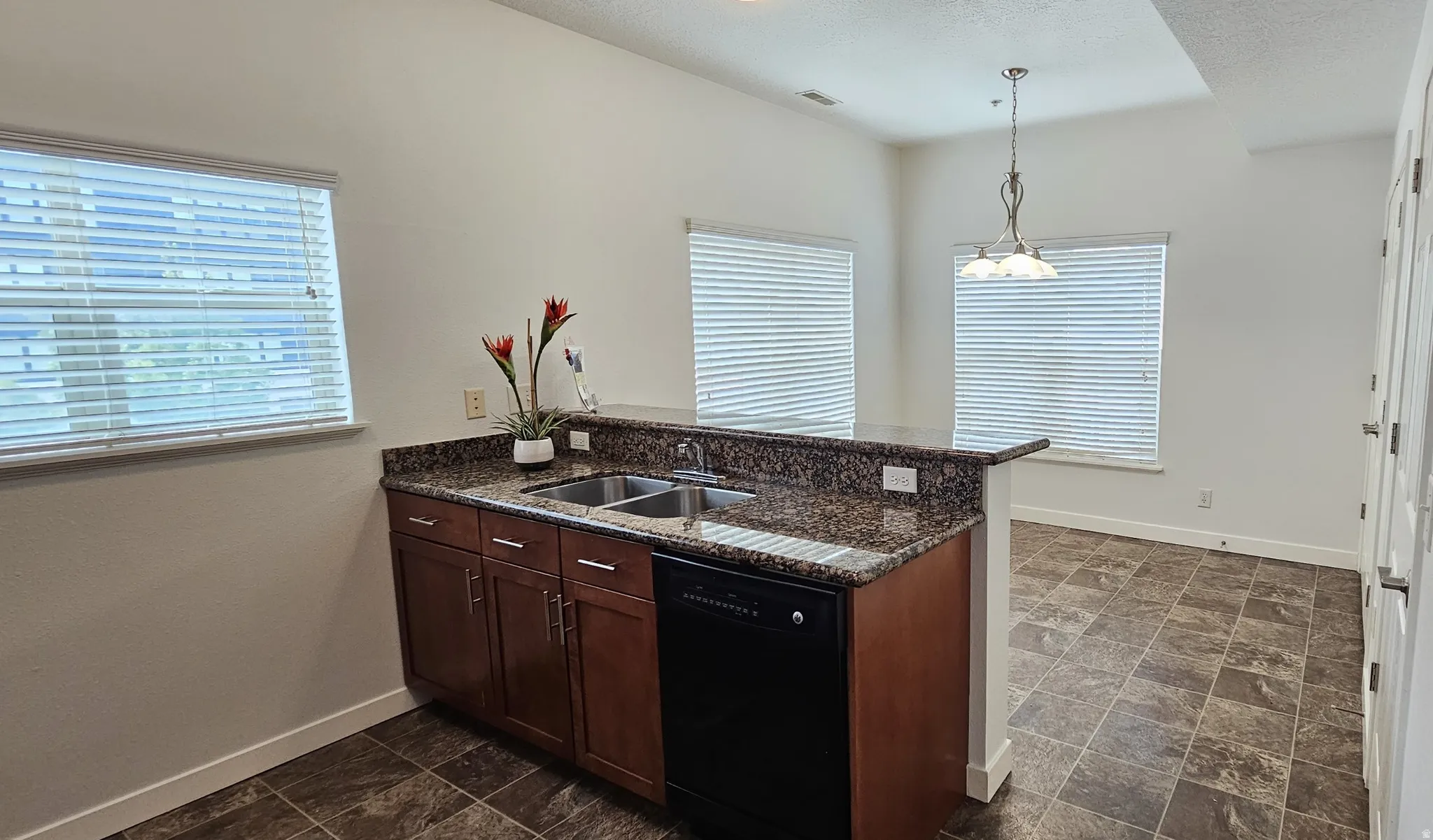 Kitchen featuring wood cabinetry, a double basin sink, and a black dishwasher