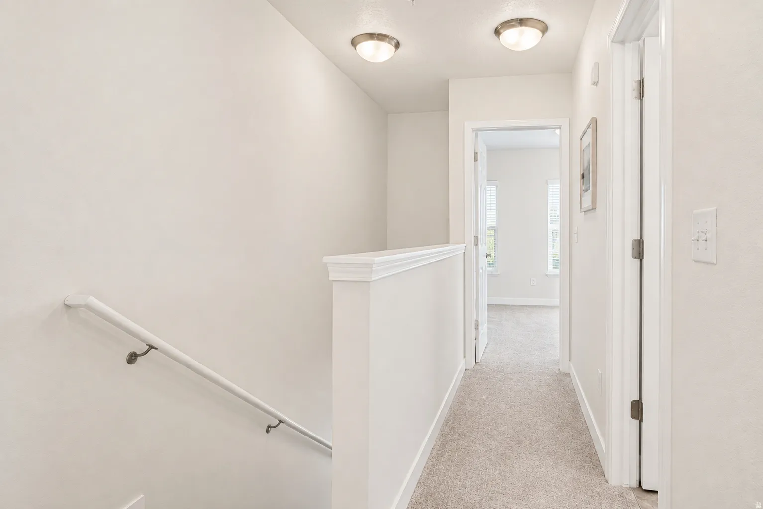 Upper-level hallway featuring carpet flooring, flush-mount lighting, and neutral wall tones