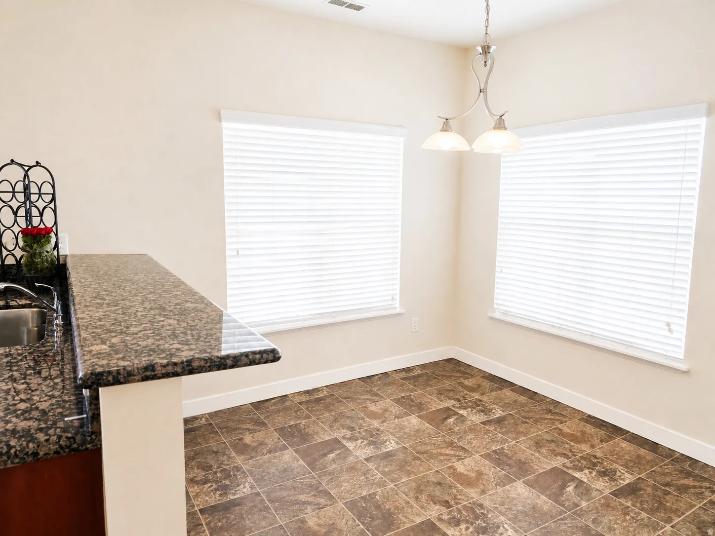 Unfurnished dining area featuring stone finish flooring and baseboards