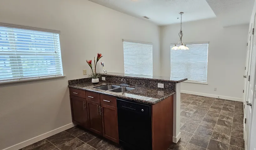 Kitchen featuring wood cabinetry, a double basin sink, and a black dishwasher
