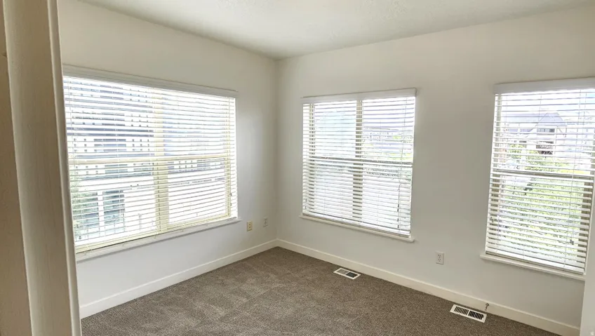 Neutral wall color, carpet flooring, and multiple windows with blinds