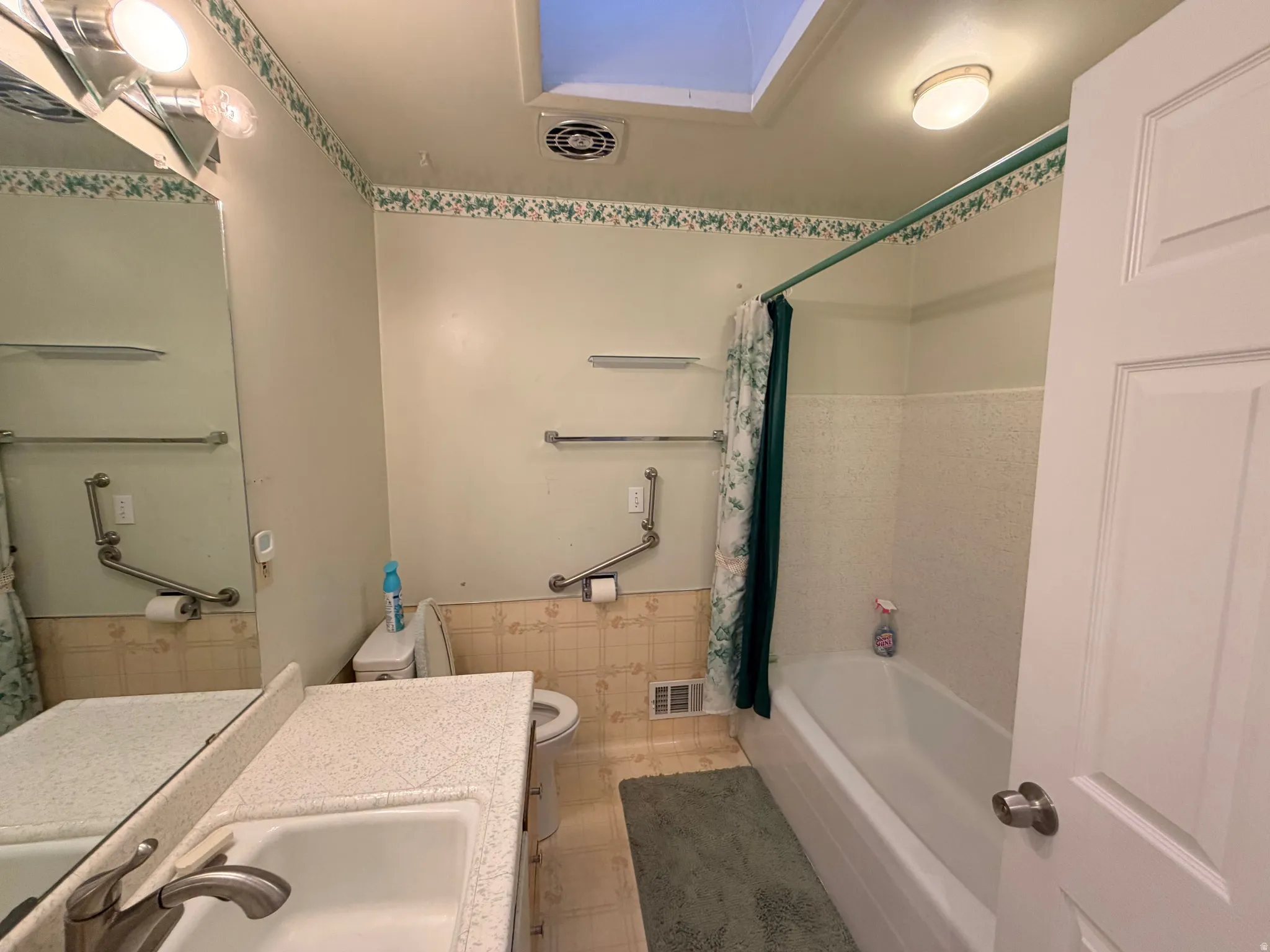 Bathroom featuring vanity and shower / bathtub combination with curtain