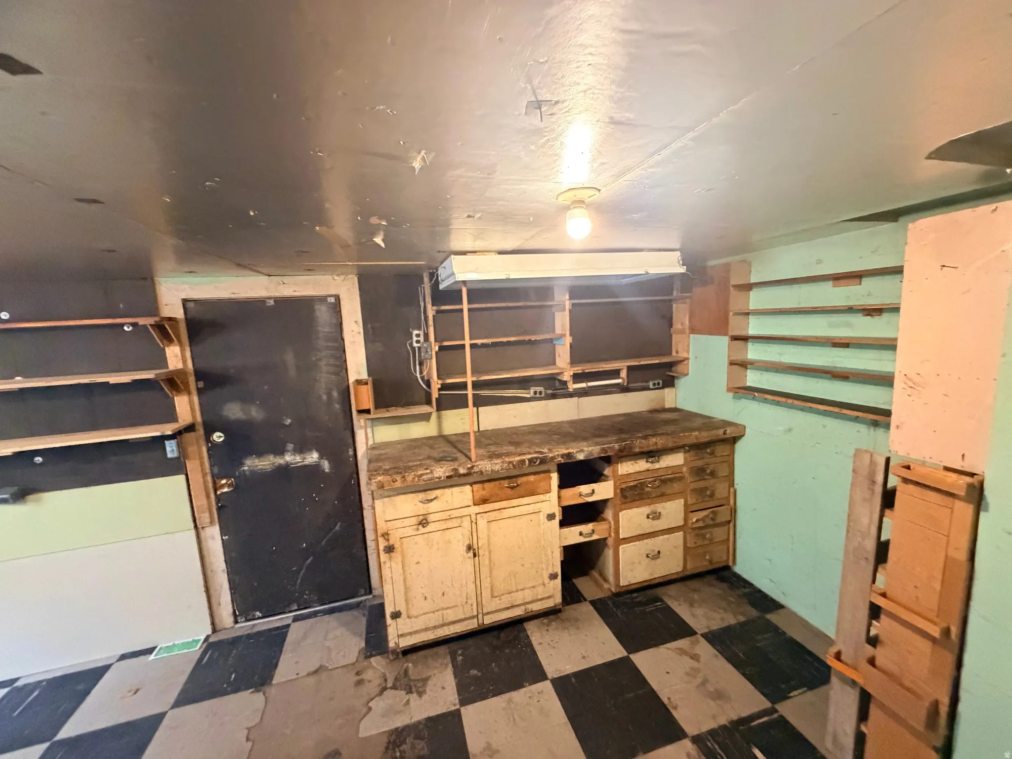 Kitchen featuring dark floors, dark countertops, and light wood finish cabinetry