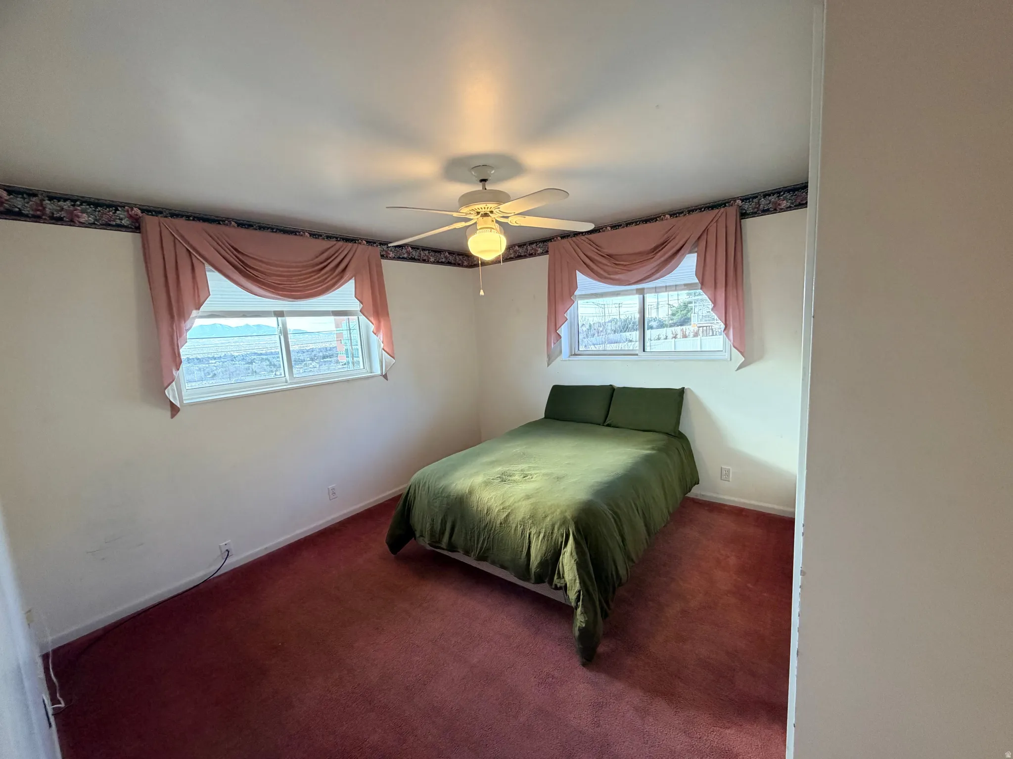 Bedroom featuring multiple windows, carpet floors, and a ceiling fan