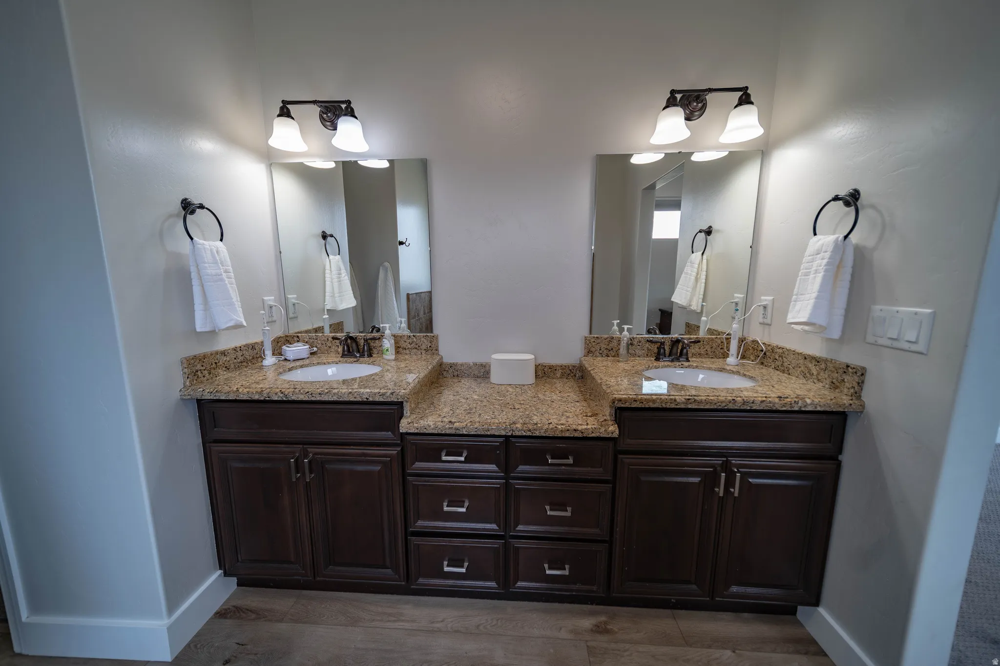 Bathroom with double vanity and dark wood-style floors