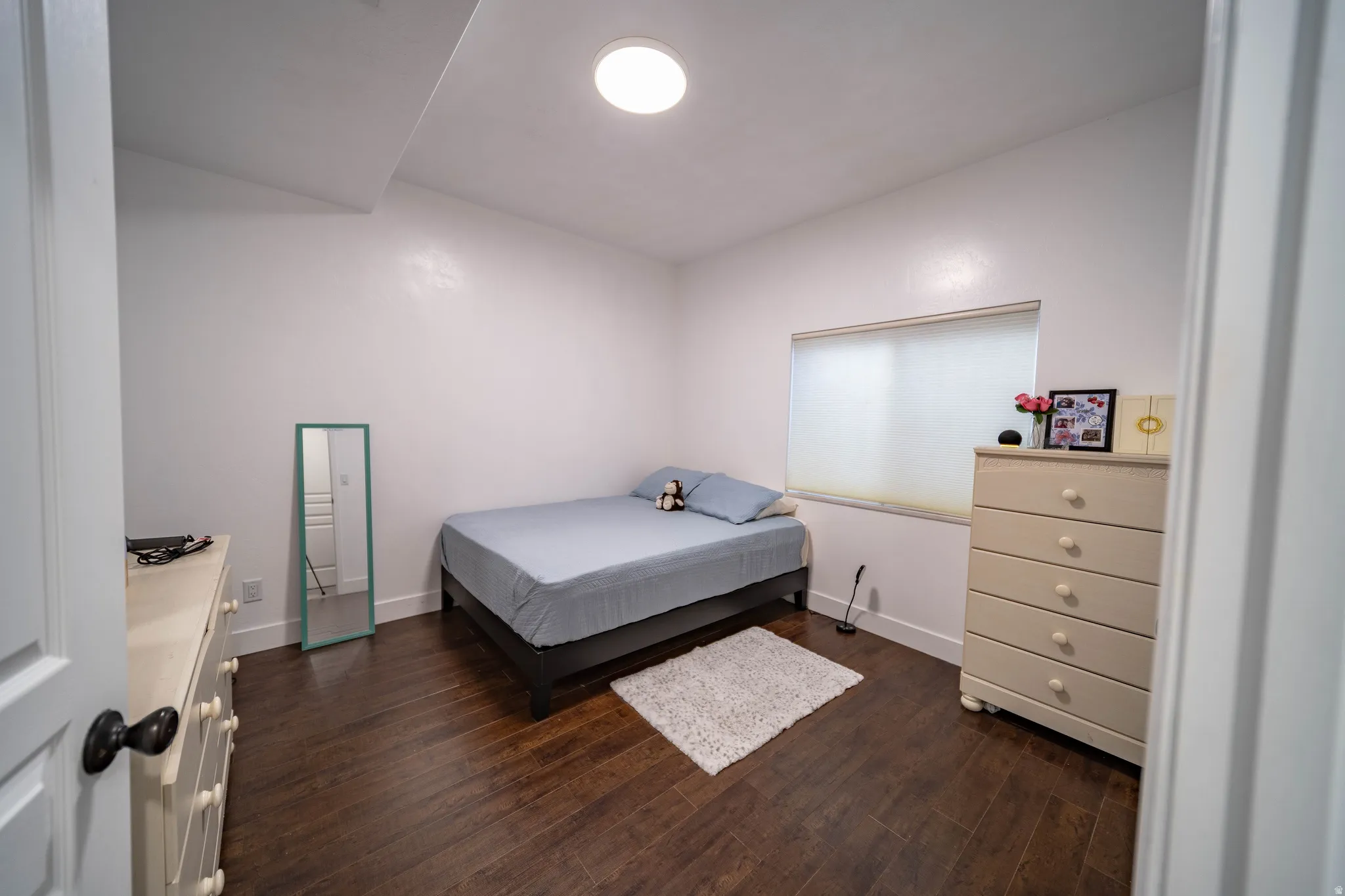 Bedroom with dark wood finished floors and baseboards