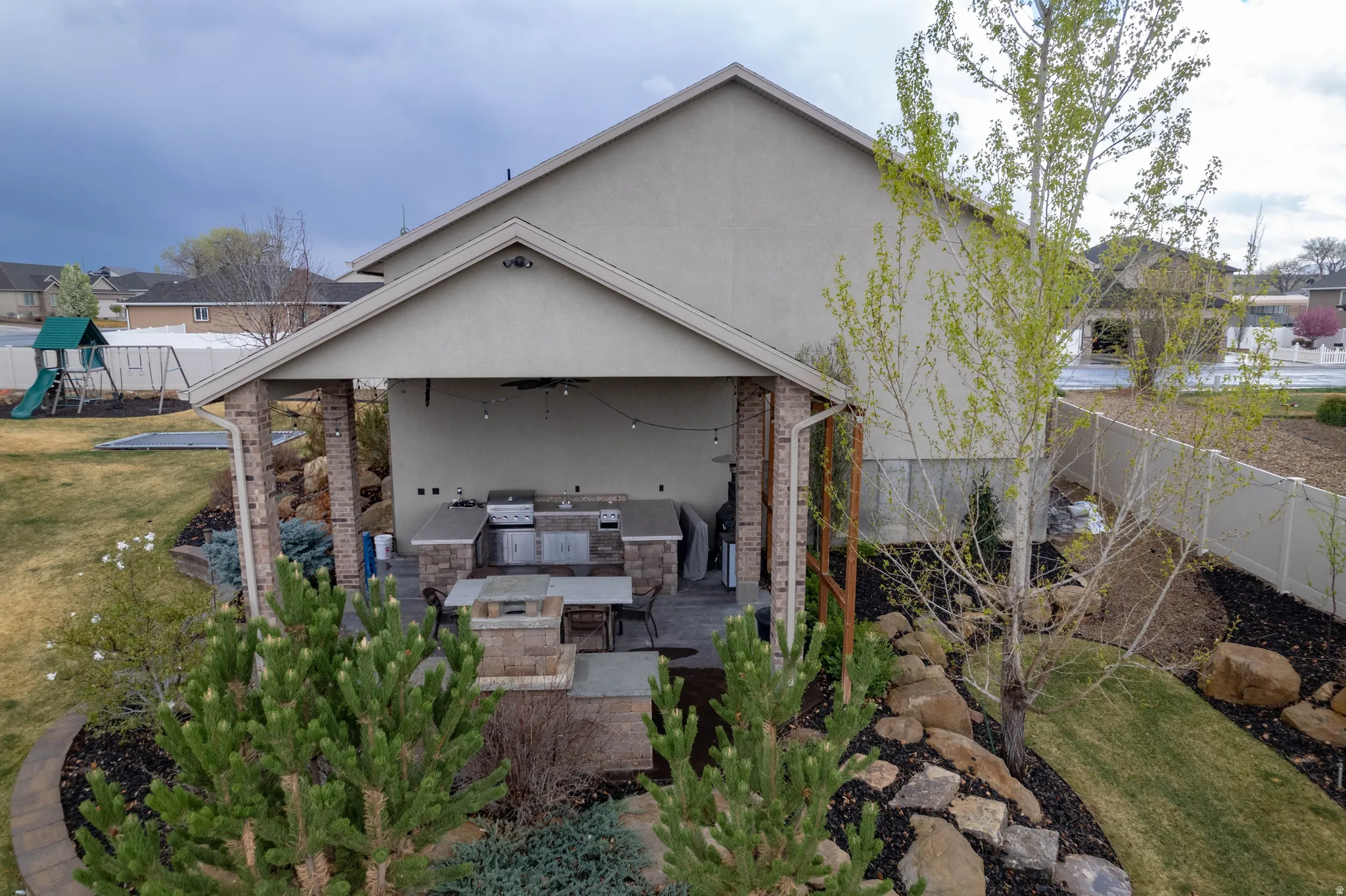 Back of house with exterior kitchen, stucco siding, a patio, a fenced backyard, and a playground