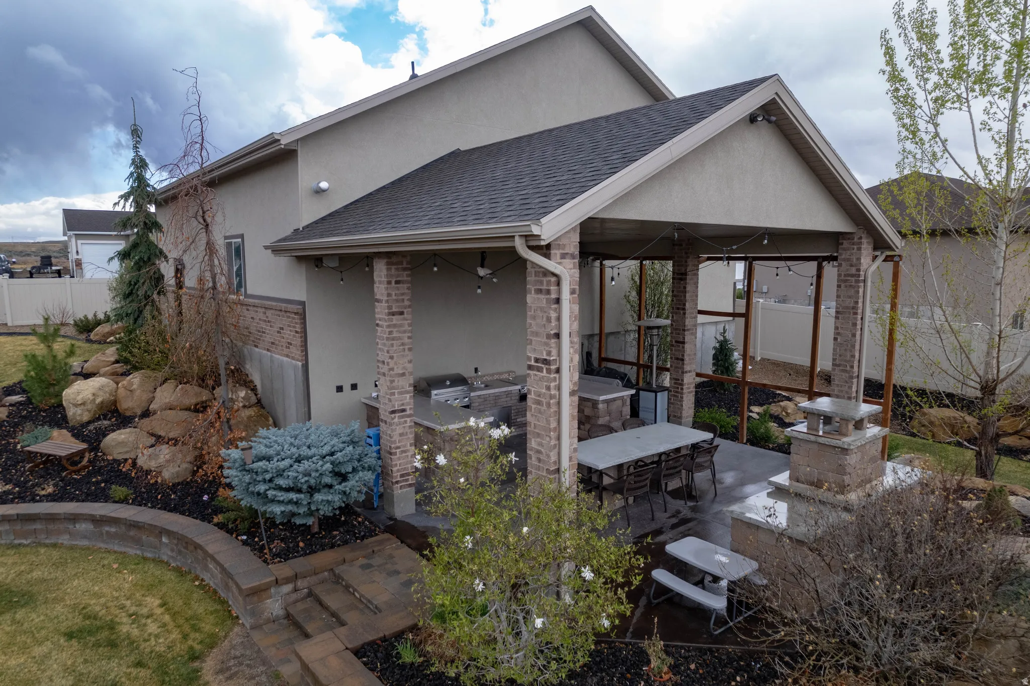 Back of house with an outdoor kitchen, stucco siding, a shingled roof, and a patio area
