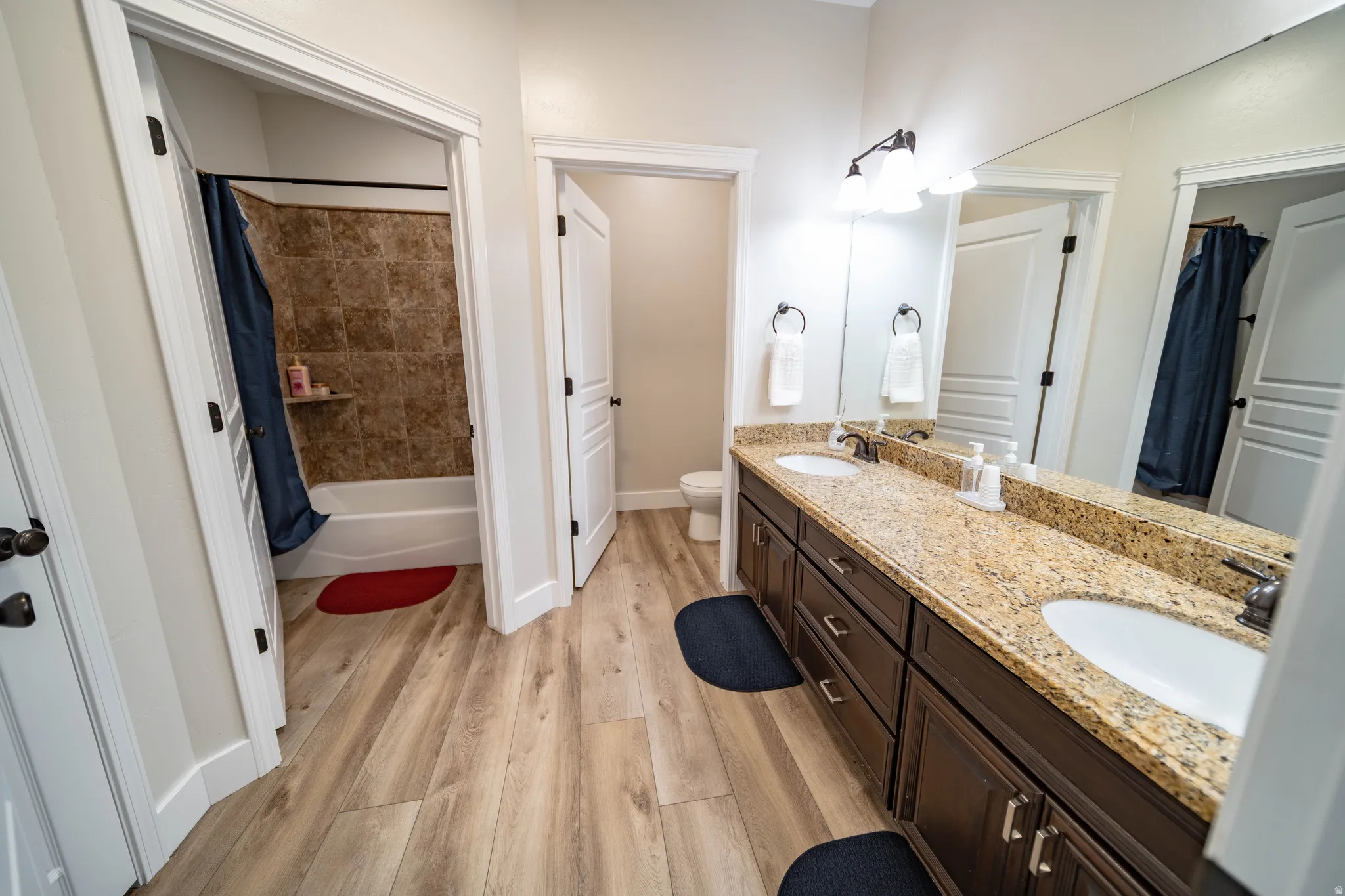 Bathroom featuring double vanity, light wood finished floors, and shower / tub combo with curtain