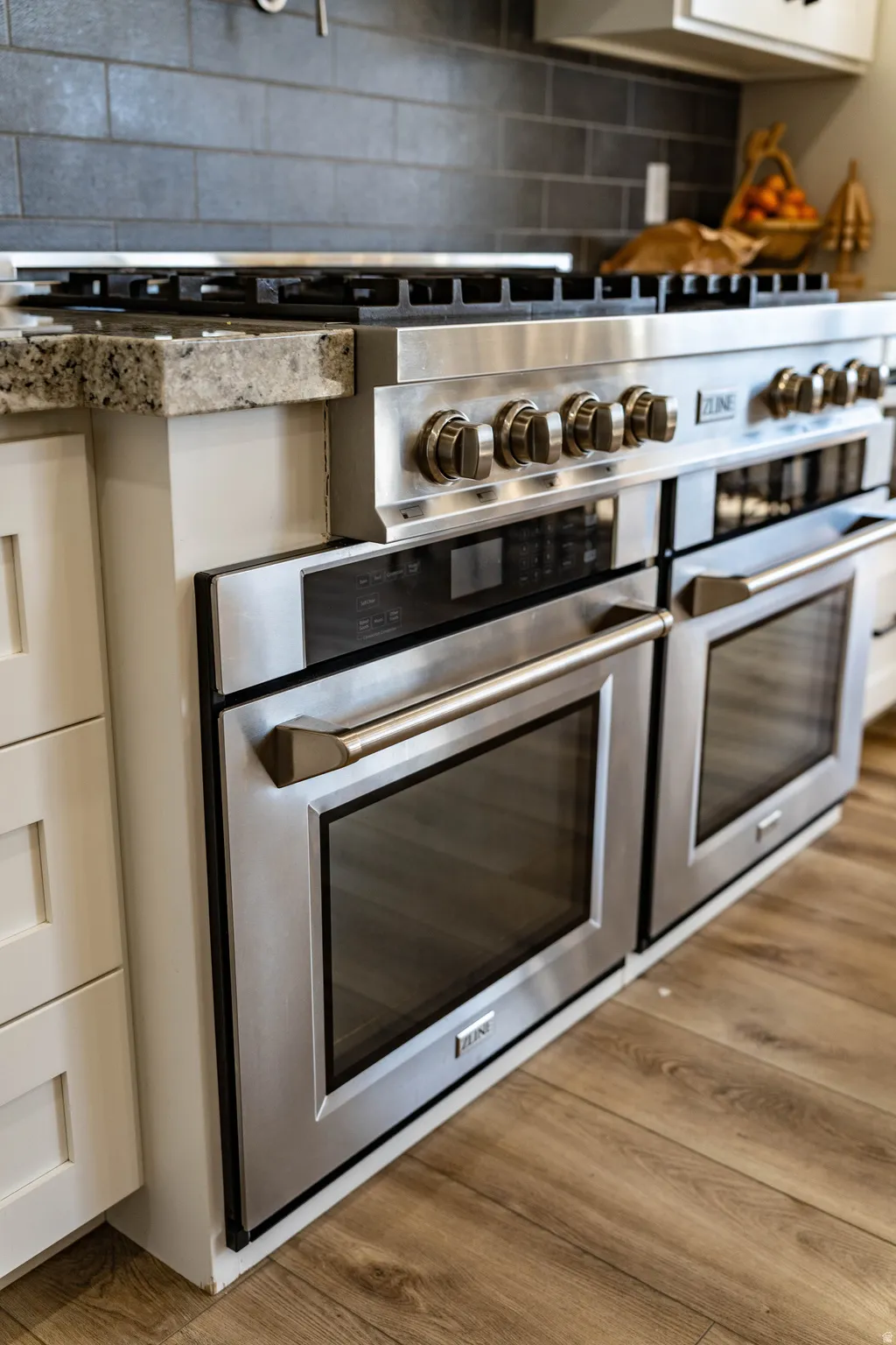 Kitchen view of range with two ovens, wood finished floors, and backsplash