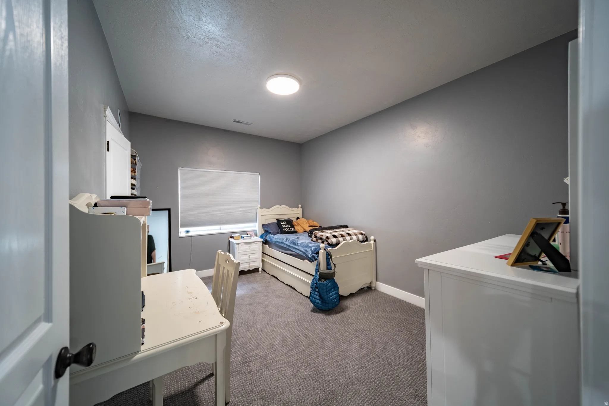 Bedroom featuring dark colored carpet and baseboards