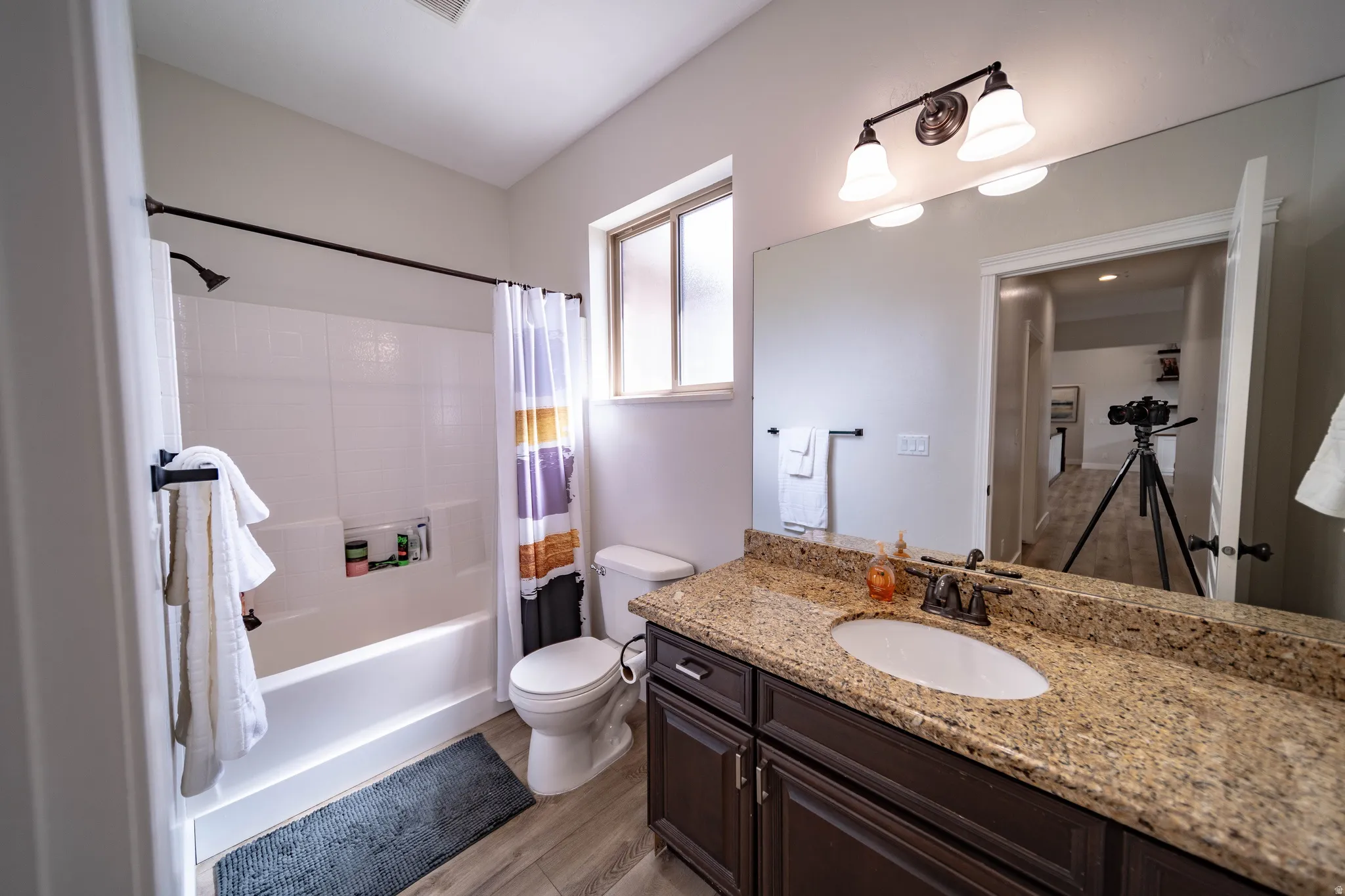 Bathroom featuring vanity, shower / tub combo, and light wood-type flooring