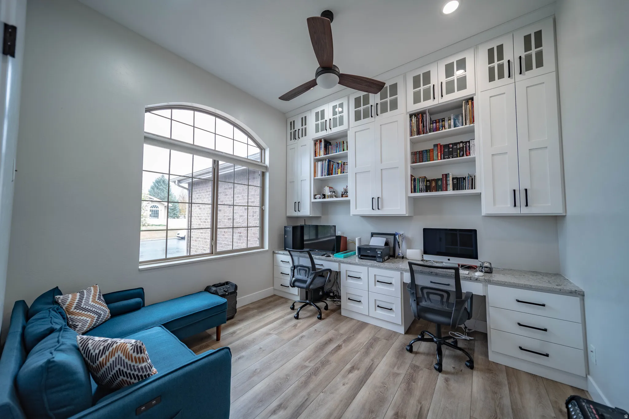 Office space featuring built in study area, light wood-style flooring, and a ceiling fan