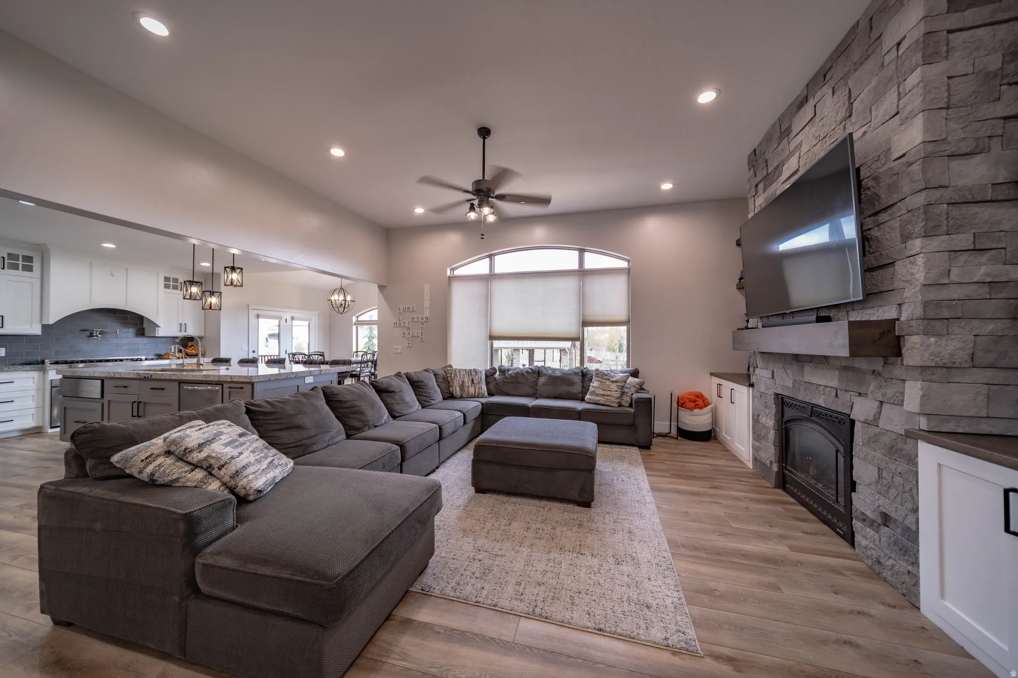 Living area featuring a ceiling fan, a chandelier, a fireplace, and wood finished floors