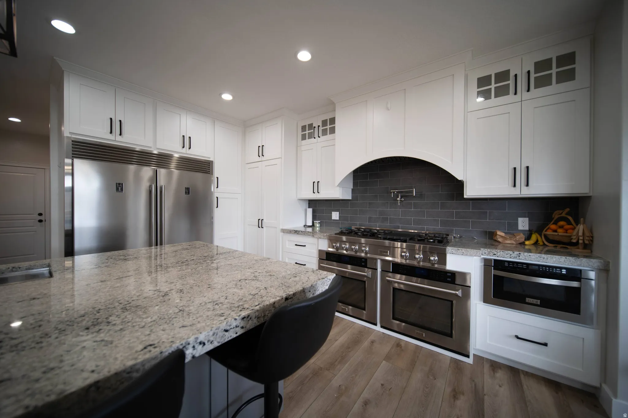 Kitchen featuring light stone countertops, stainless steel appliances, white cabinetry, and recessed lighting