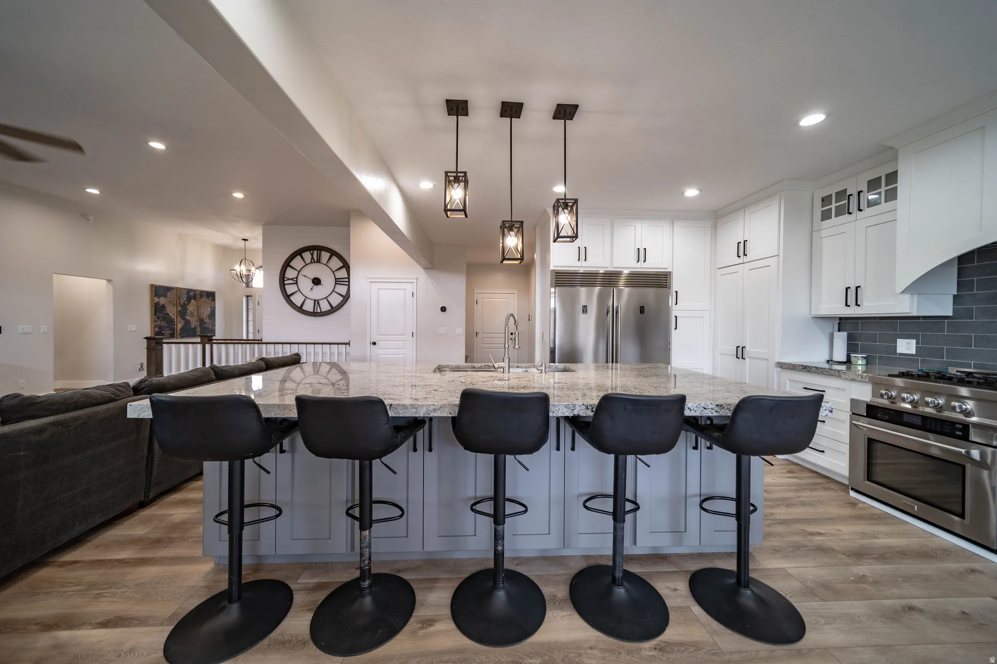 Kitchen with white cabinetry, light wood-style flooring, stainless steel appliances, and a large island with sink
