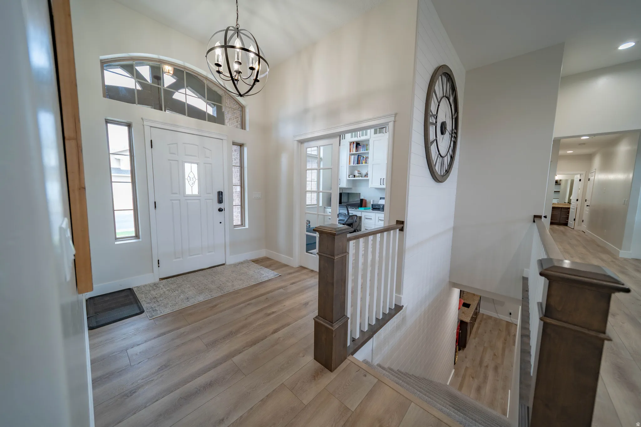 Entryway featuring light wood finished floors, a chandelier, and a high ceiling