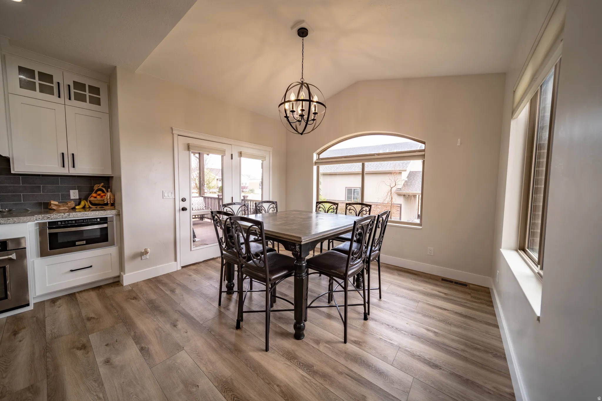 Dining area with vaulted ceiling, wood finished floors, and a chandelier