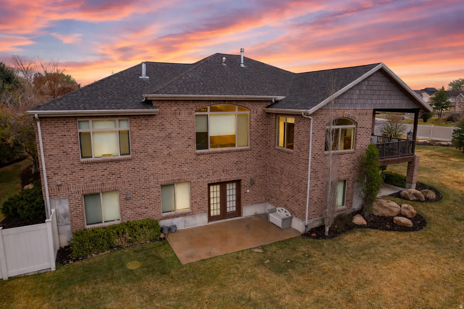 Rear view of house featuring brick siding, a patio area, french doors, and roof with shingles