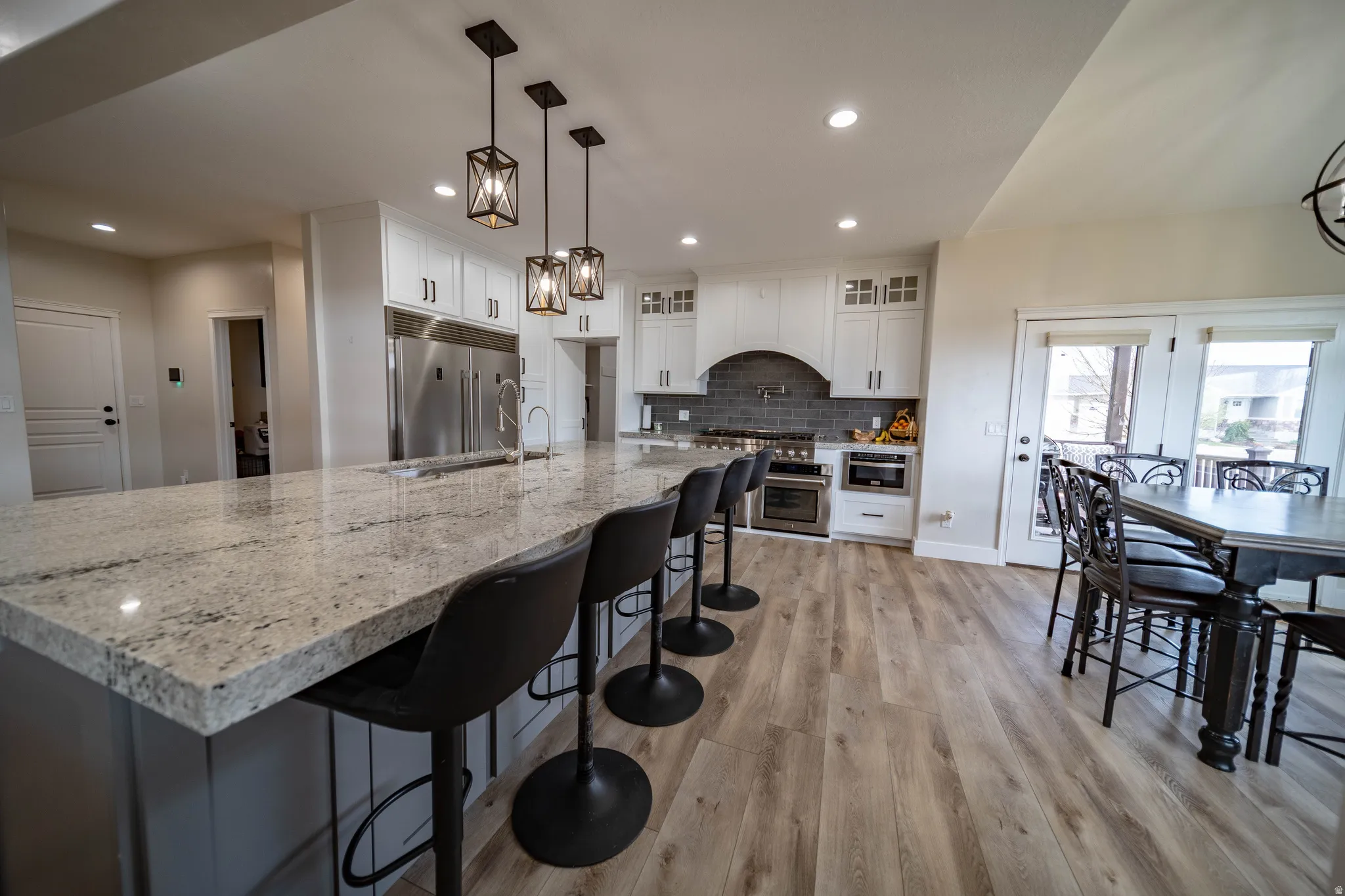 Kitchen featuring white cabinetry, light stone countertops, light wood-type flooring, a chandelier, and a kitchen breakfast bar