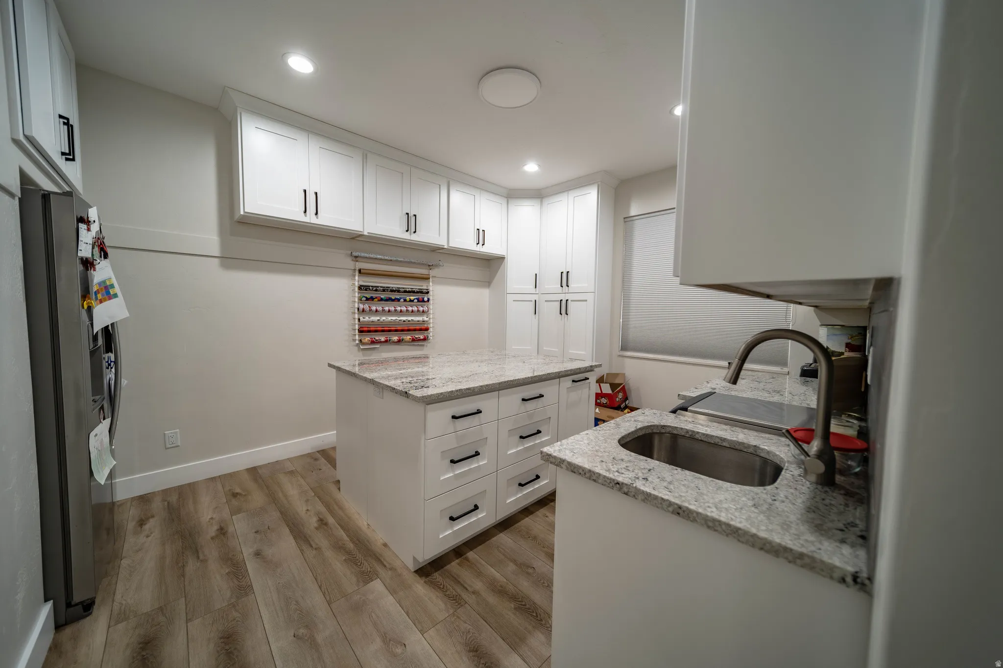 Kitchen featuring white cabinetry, light wood-style floors, light stone countertops, stainless steel fridge with ice dispenser, and recessed lighting