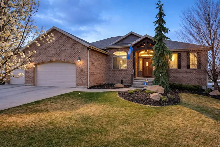 View of front facade with a garage, concrete driveway, a front lawn, and brick siding