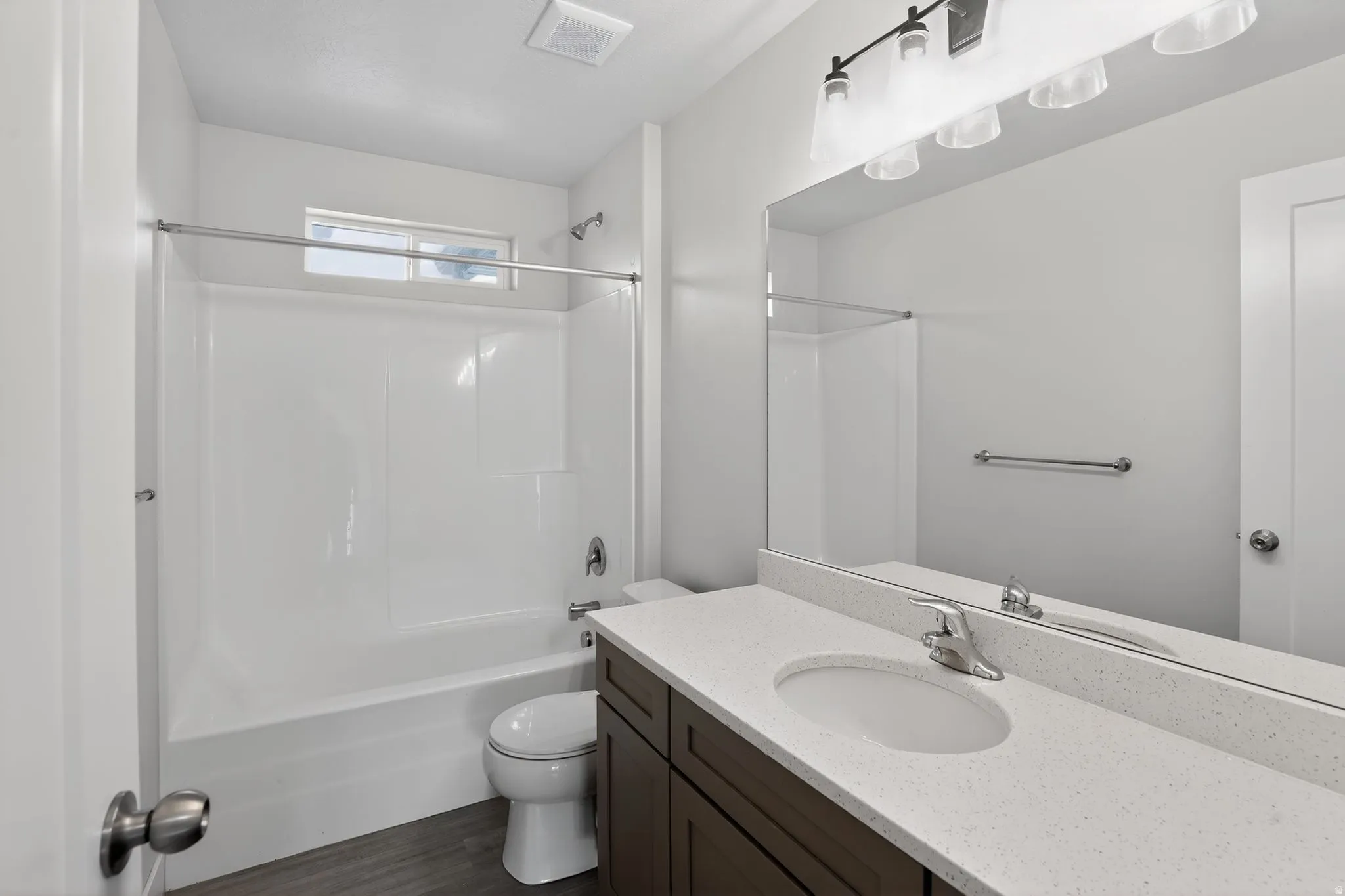 Bathroom featuring vanity, shower / tub combination, and dark wood-type flooring