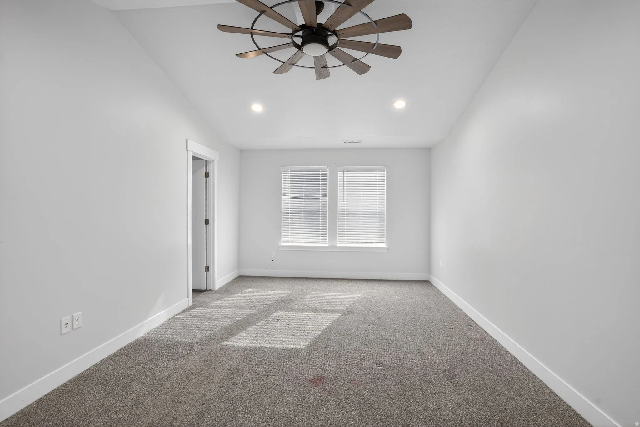 Empty room featuring carpet flooring, ceiling fan, lofted ceiling, and recessed lighting