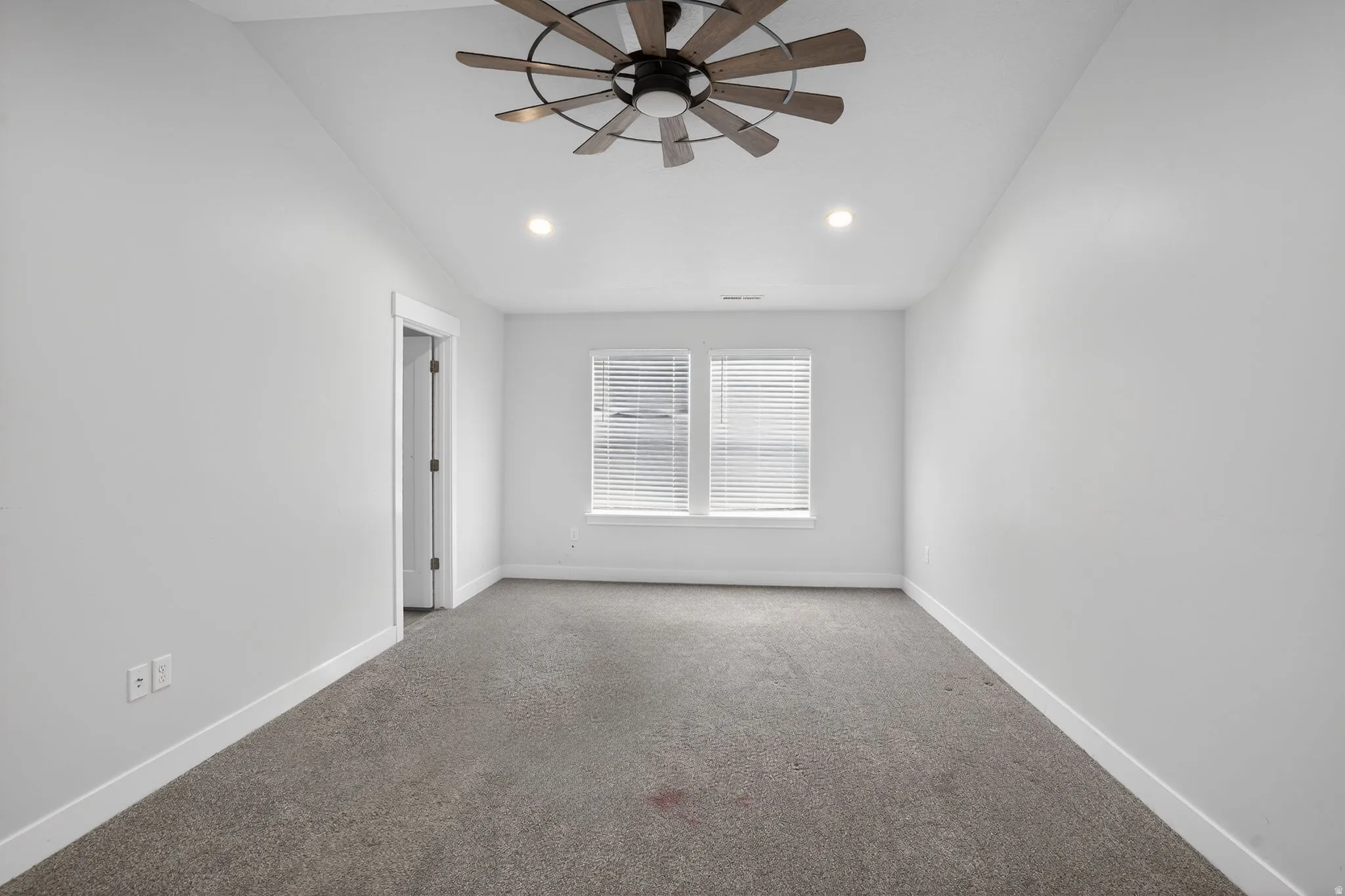 Carpeted empty room with ceiling fan and lofted ceiling