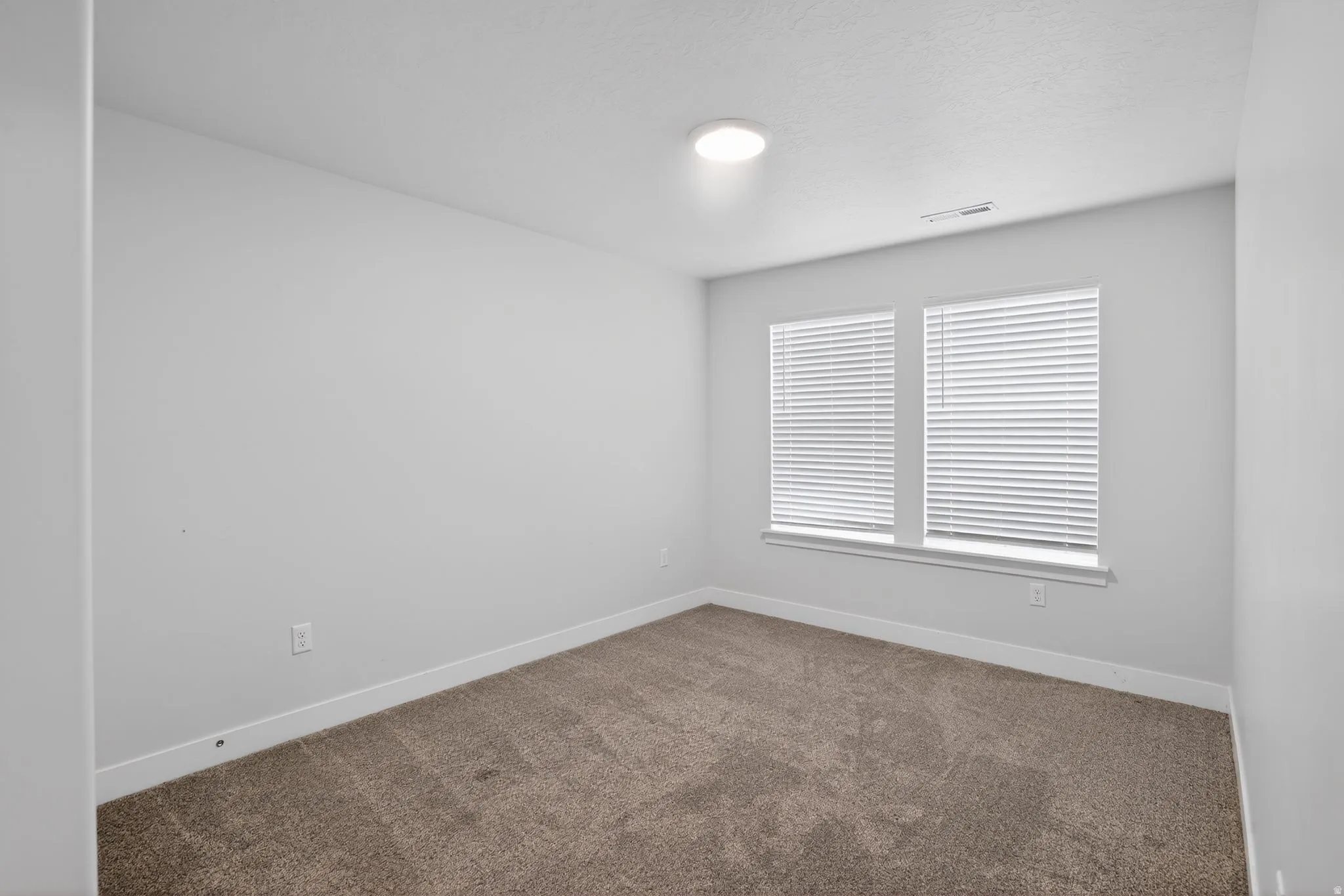 Empty room with dark colored carpet and baseboards