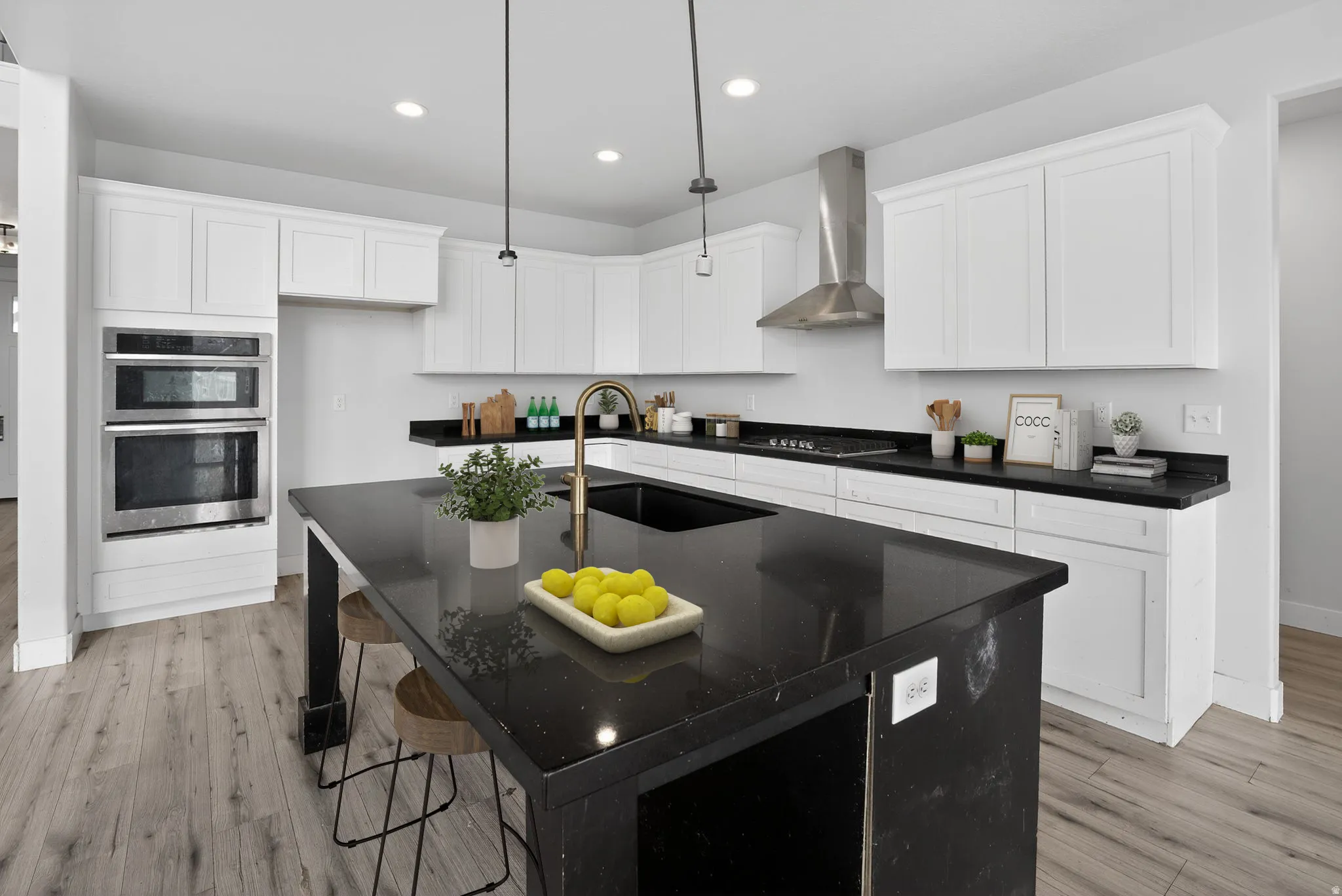 Kitchen with a center island with sink, a breakfast bar, white cabinetry, stainless steel appliances, and light wood-style floors
