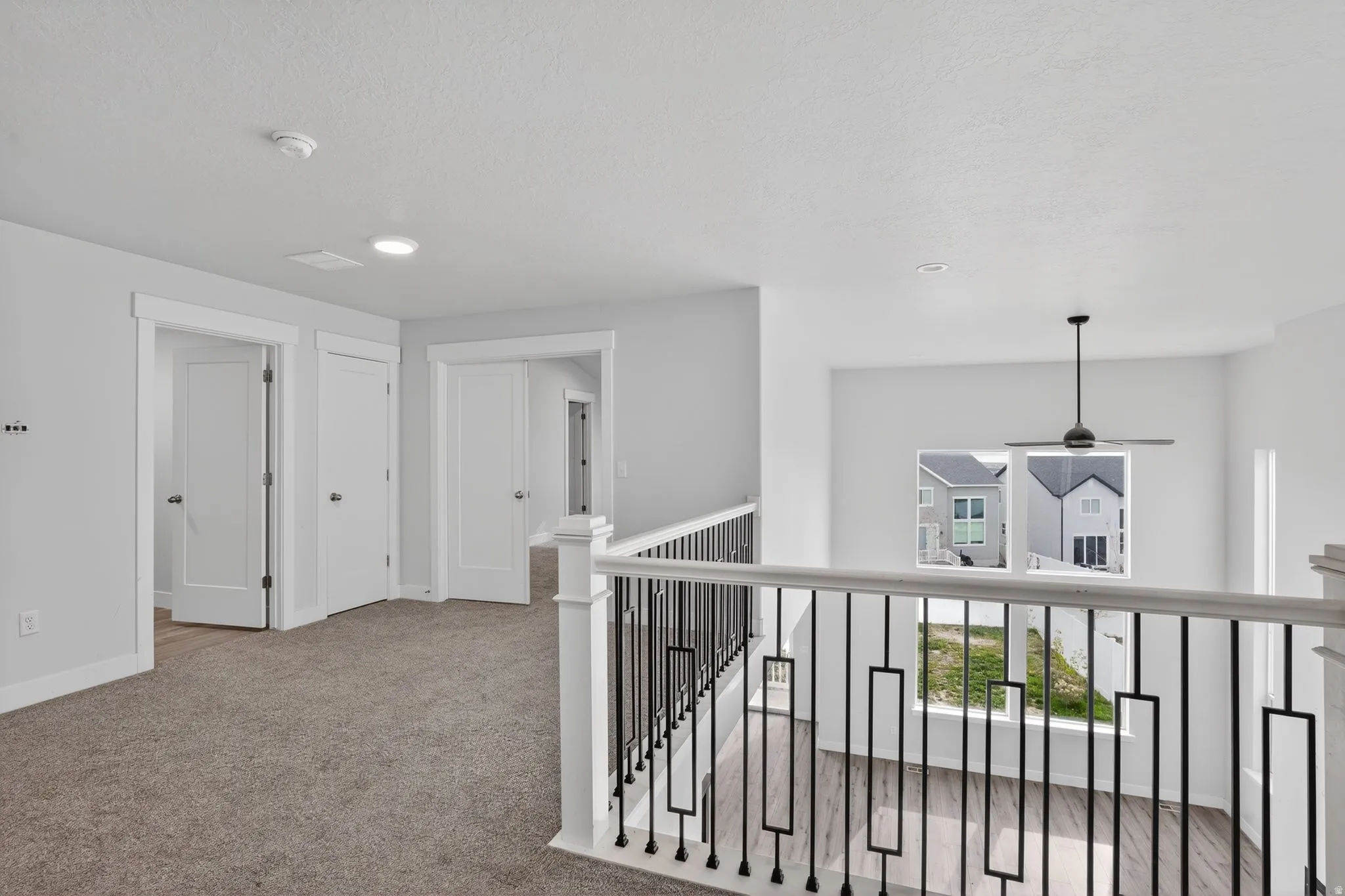Hall with light colored carpet and a textured ceiling
