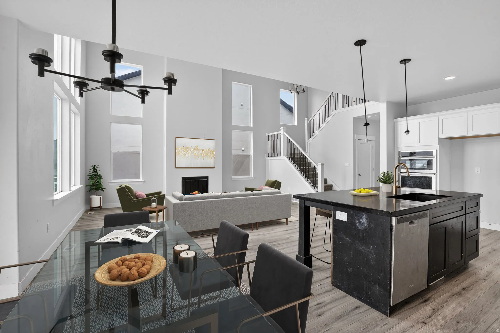 Kitchen with a lit fireplace, open floor plan, an island with sink, stainless steel appliances, and a high ceiling