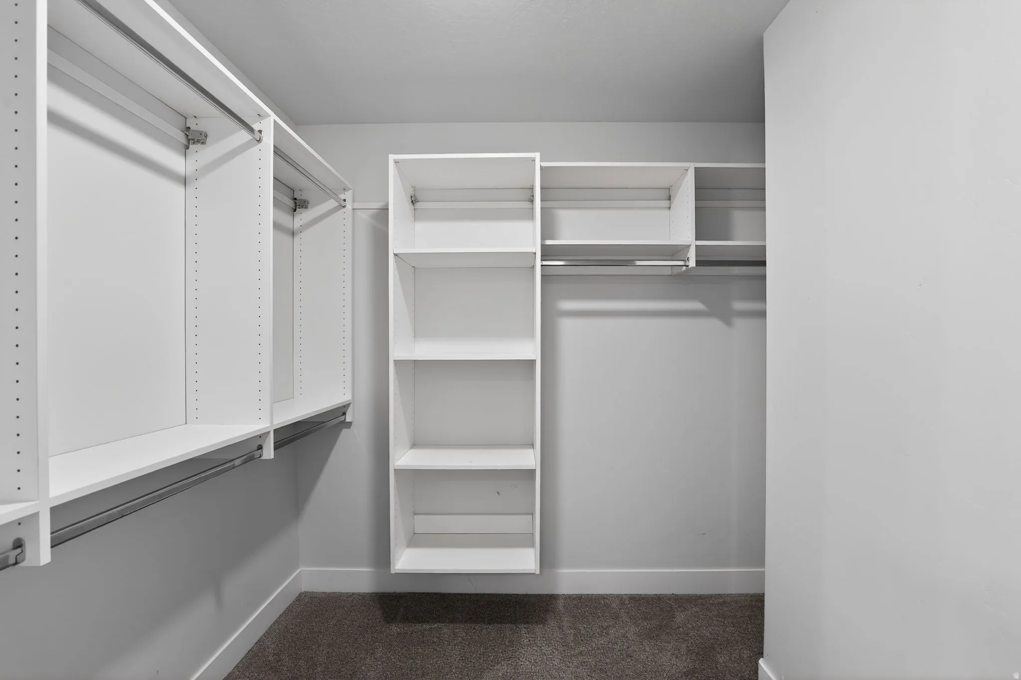 Walk in closet featuring dark colored carpet